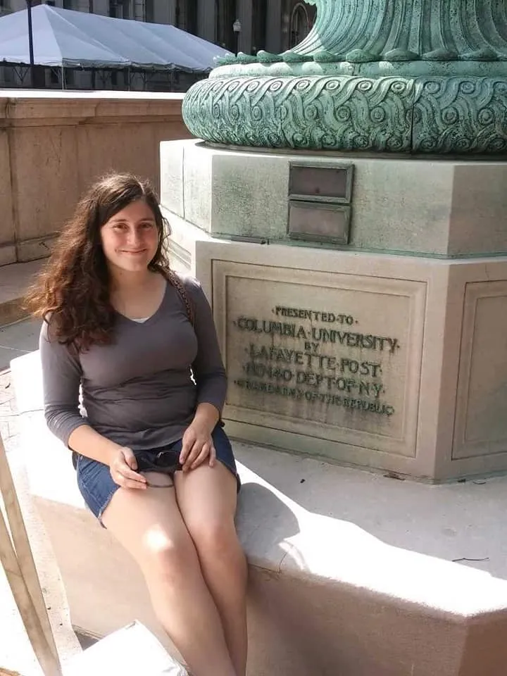 Emily Weisenberger sitting by a flagpole