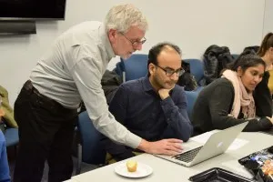 A man helping another man with work on a laptop