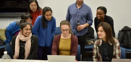 A group of people gathered around a laptop