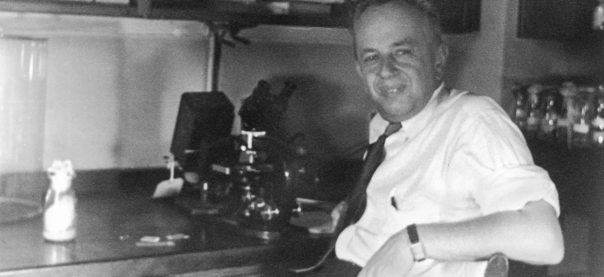 Dobzhansky sitting at desk with microscope. Photo Credit to American Philosophical Society. 