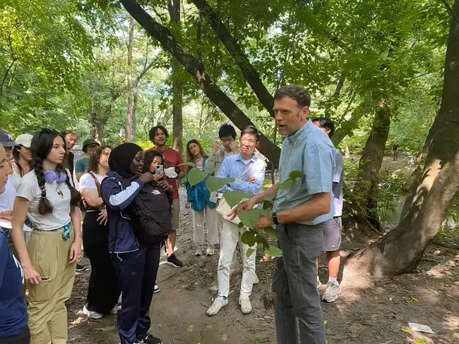 Matthew Palmer shows students a knotweed plant found along the trails of Bronx Park East, highlighting its invasive nature. Photo: Jennifer Wu